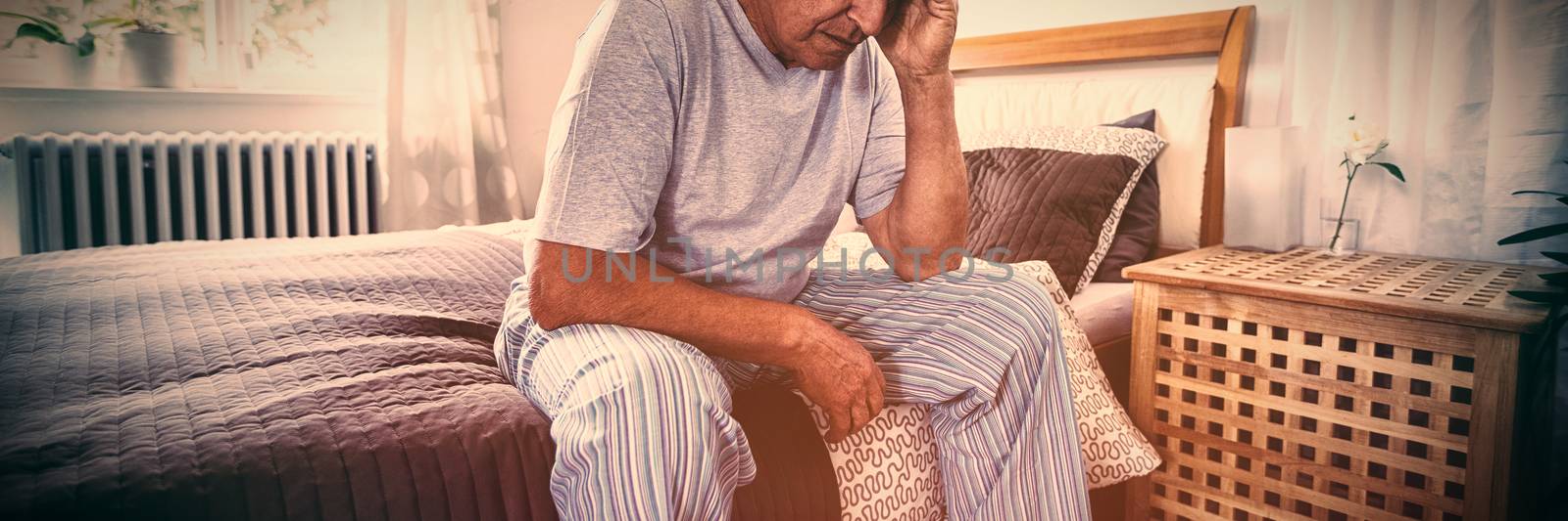 Frustrated senior man sitting on bed in bedroom