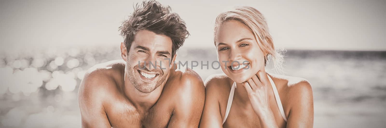 Portrait of happy young couple lying on beach