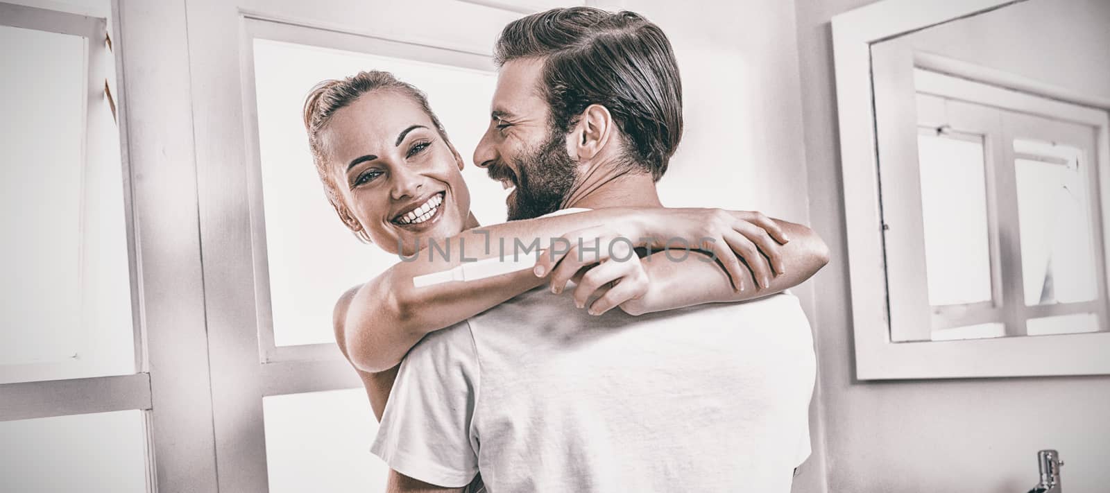 Woman holding pregnancy test while embracing man at home