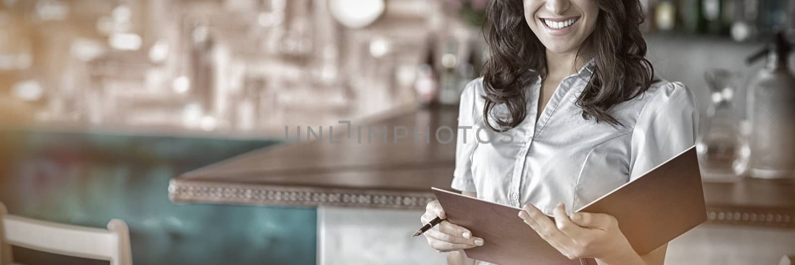 Portrait of smiling waitress holding a file in restaurant