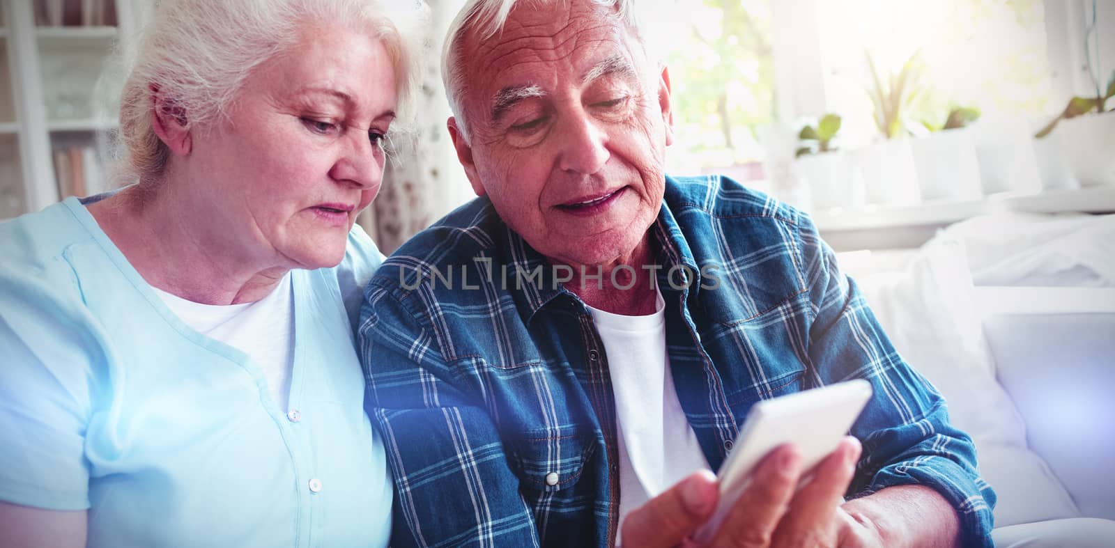 Senior couple using mobile phone at home