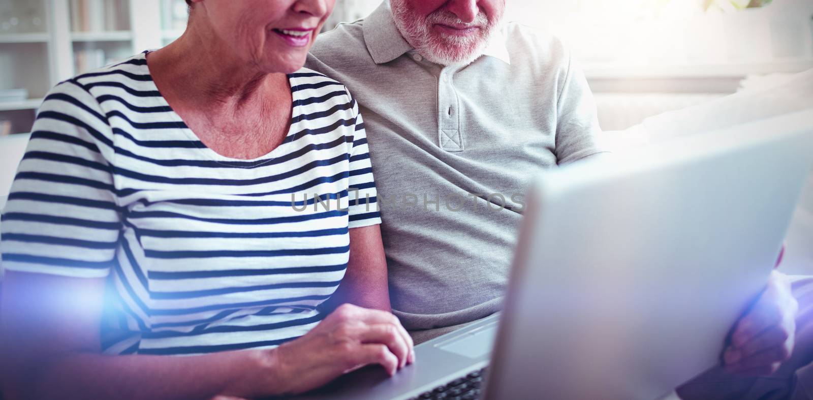 Senior couple using laptop in living room by Wavebreakmedia