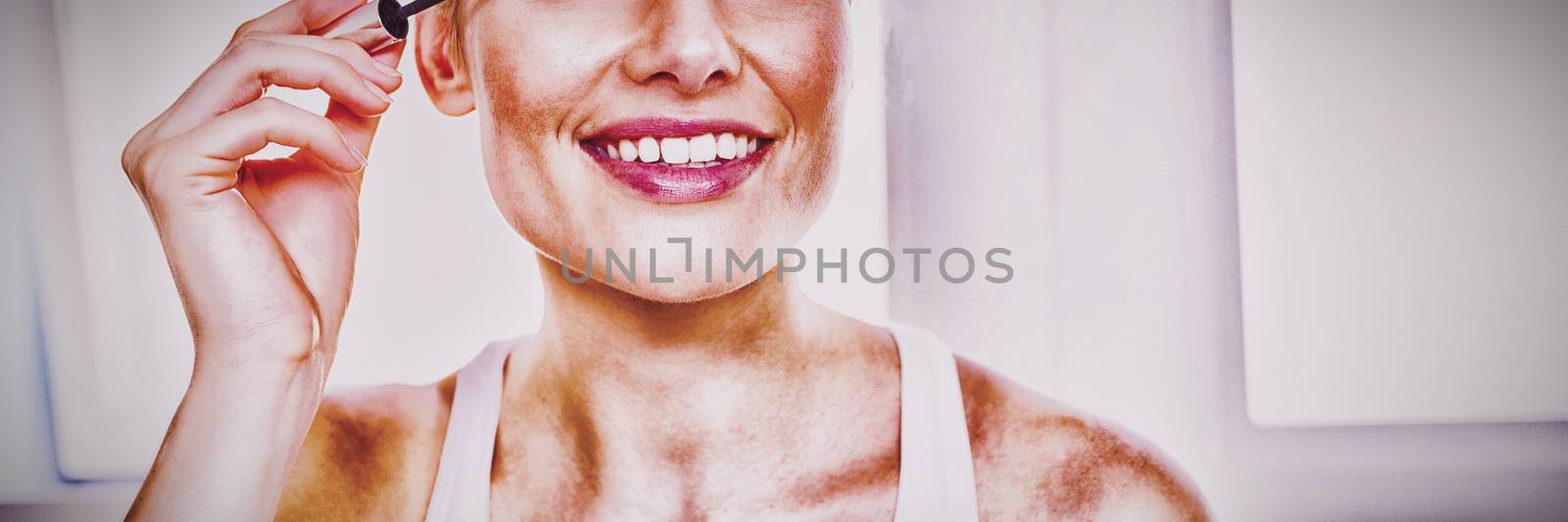 Young woman applying mascara in bathroom at home