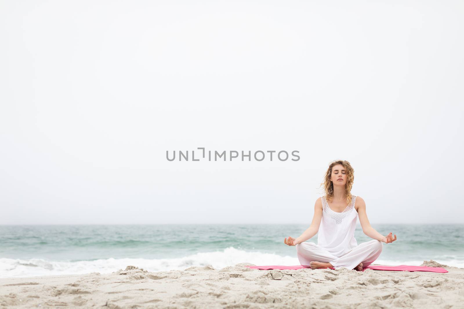 Woman performing yoga on the beach by Wavebreakmedia