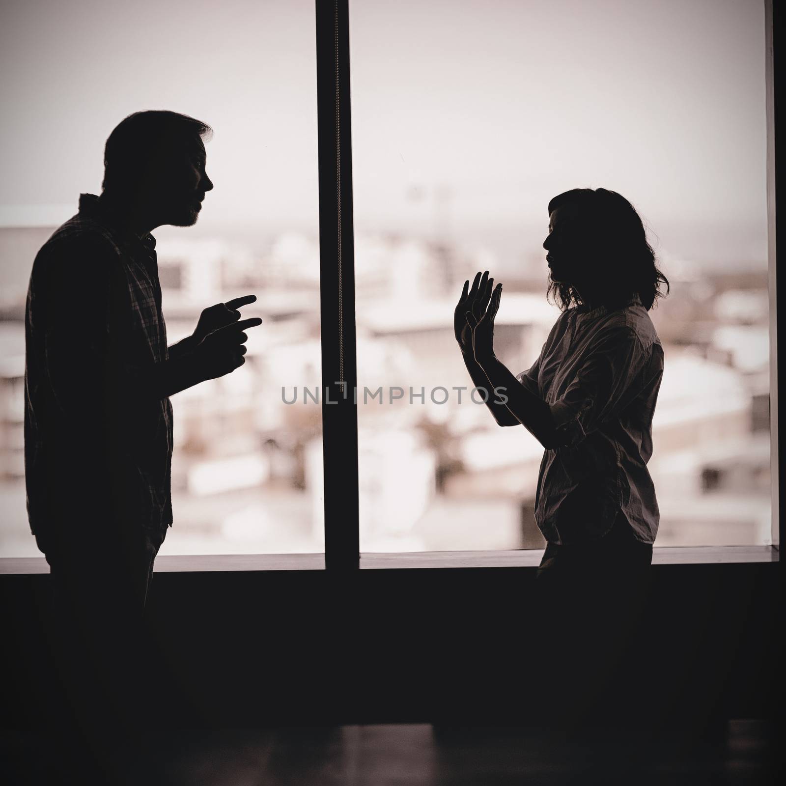 Couple arguing near the window in office