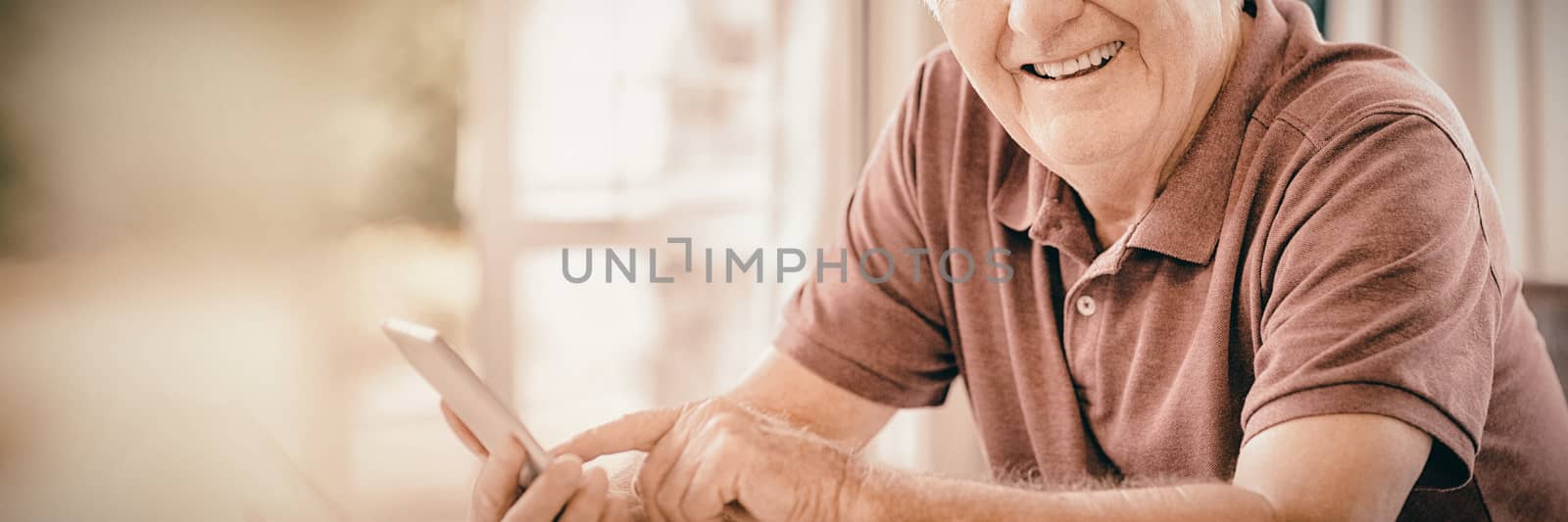 Portrait of smiling senior man using mobile phone at home
