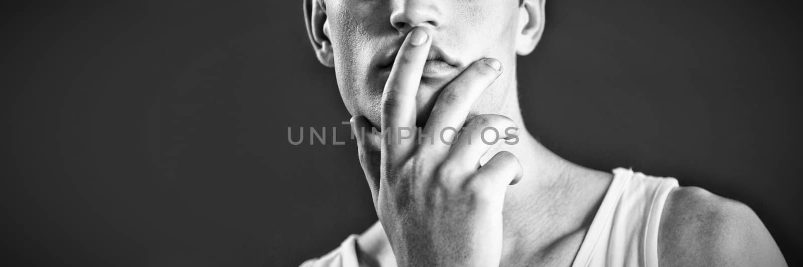 Androgynous man posing with finger on lips against green background