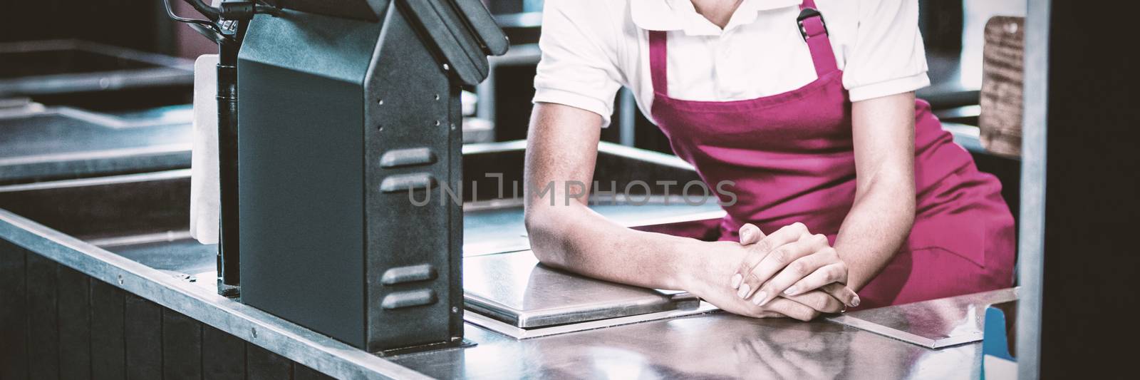 Portrait of smiling female staff sitting at cash counter in supermarket