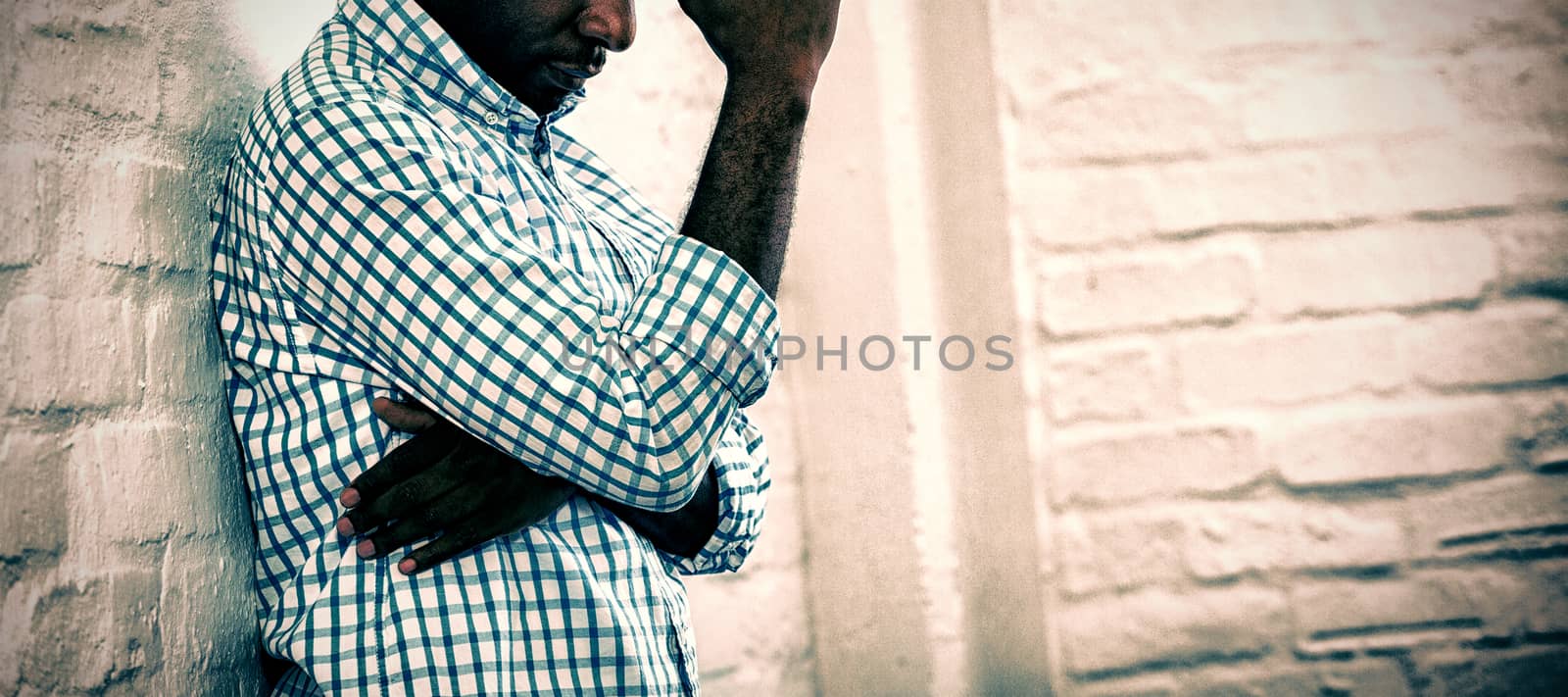 Upset man with eyes closed leaning against a wall in office, Side view
