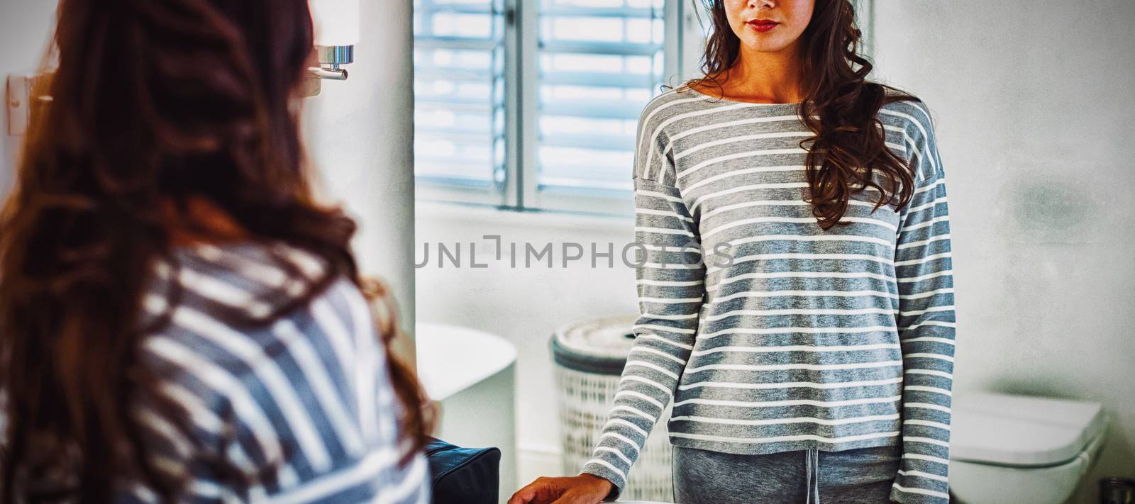 Woman looking at herself in the bathroom mirror at home