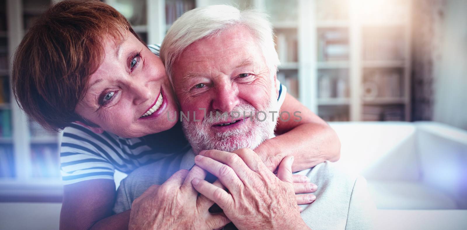 Portrait of senior woman embracing man in living room