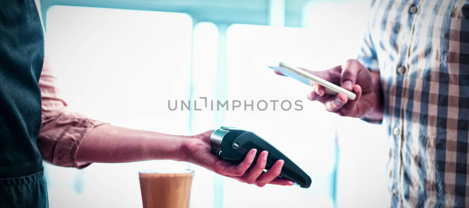 Man making payment through NFC technology in cafe by Wavebreakmedia
