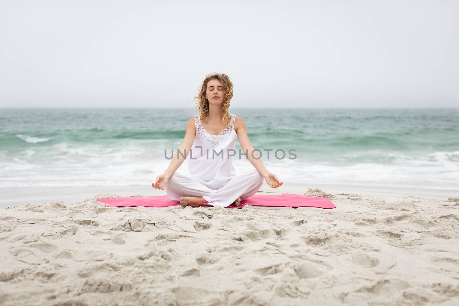 Front view of beautiful caucasian woman performing yoga at beach on sunny day