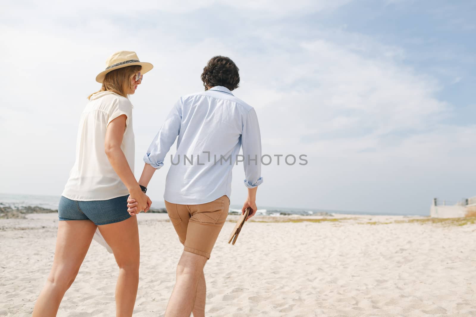 Low angle view of young Caucasian couple walking at beach on a sunny day 