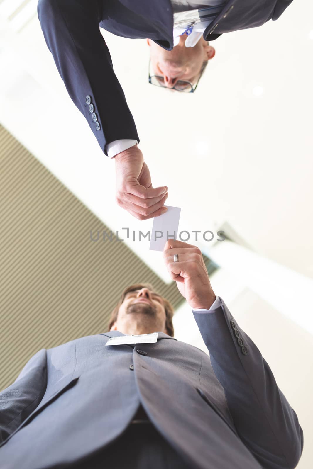 Upward view of business people exchanging business card by Wavebreakmedia