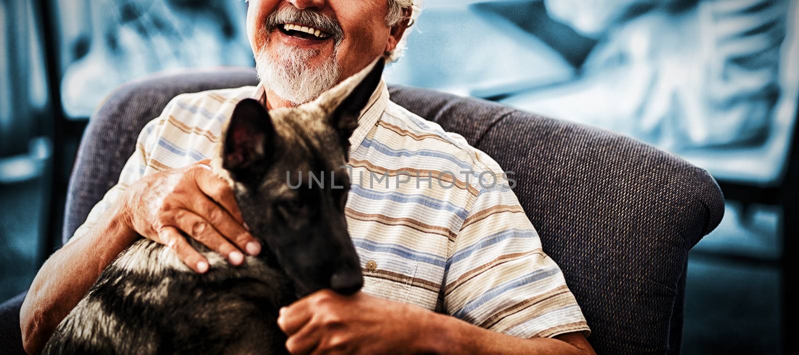 Portrait of smiling senior man sitting with puppy on chair at retirement home