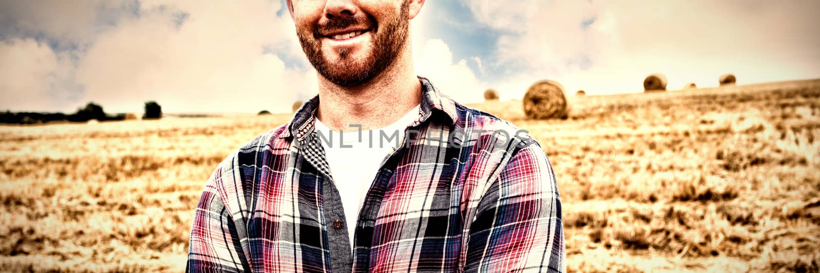 Farmer standing with arms crossed in field on sunny day
