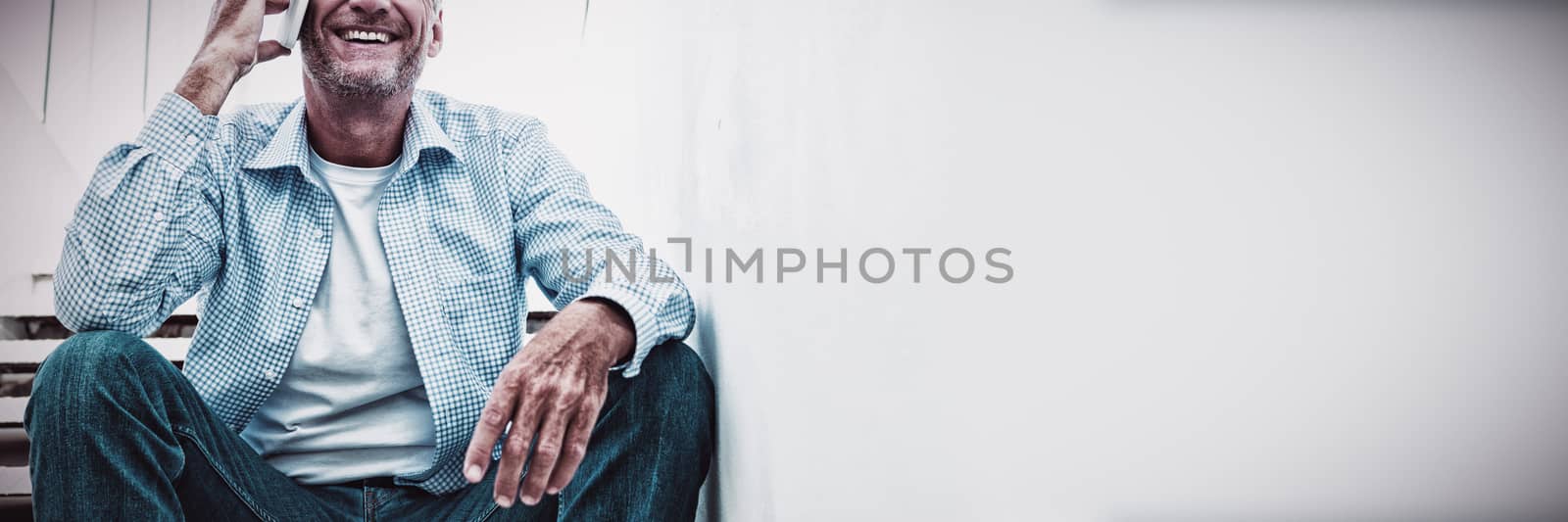 Smiling mature man using mobile phone on steps at home