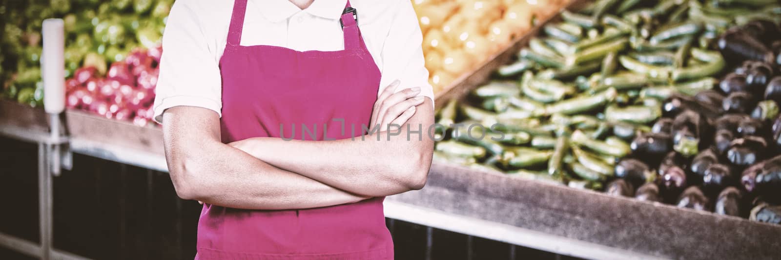 Portrait of smiling female staff standing with arms crossed in organic section of super market