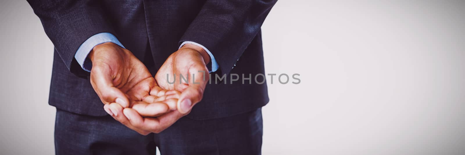 Midsection of businessman with hands cupped standing against white background