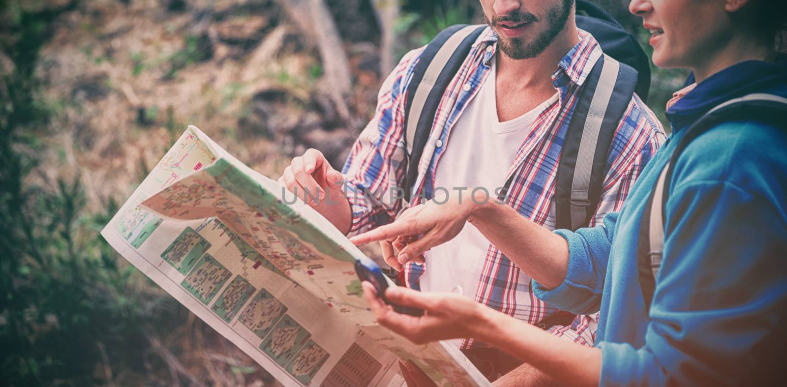 Young couple discussing over map in forest
