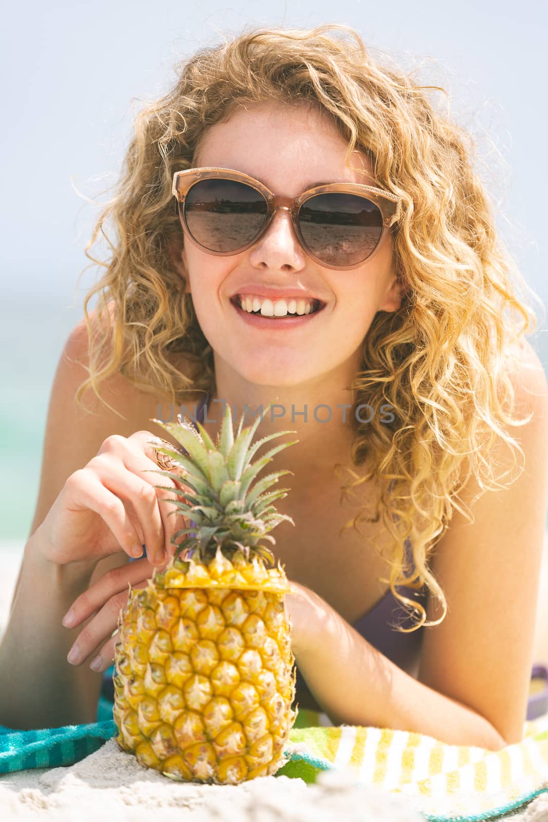 Close up of Caucasian woman lying at beach while having pineapple  
