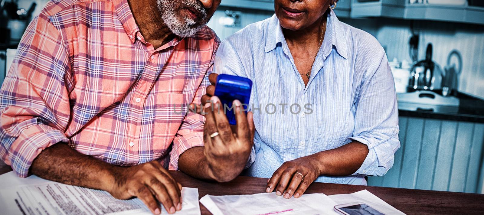 Couple using calculator while discussing over document by Wavebreakmedia