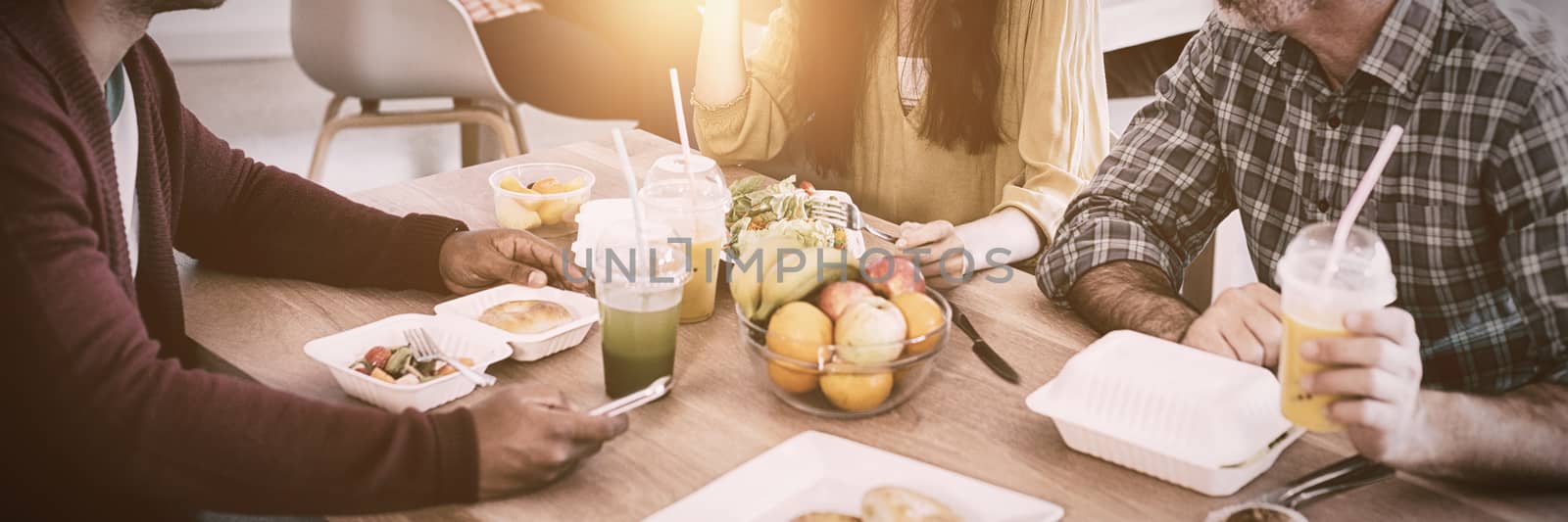 Creative business team discussing while having meal by Wavebreakmedia