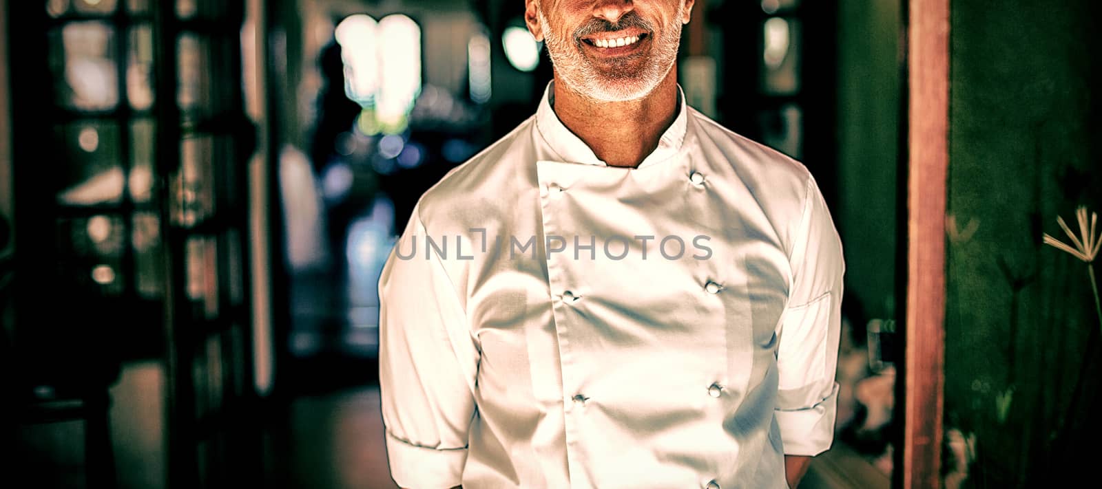 Portrait of chef standing with hands behind back in restaurant