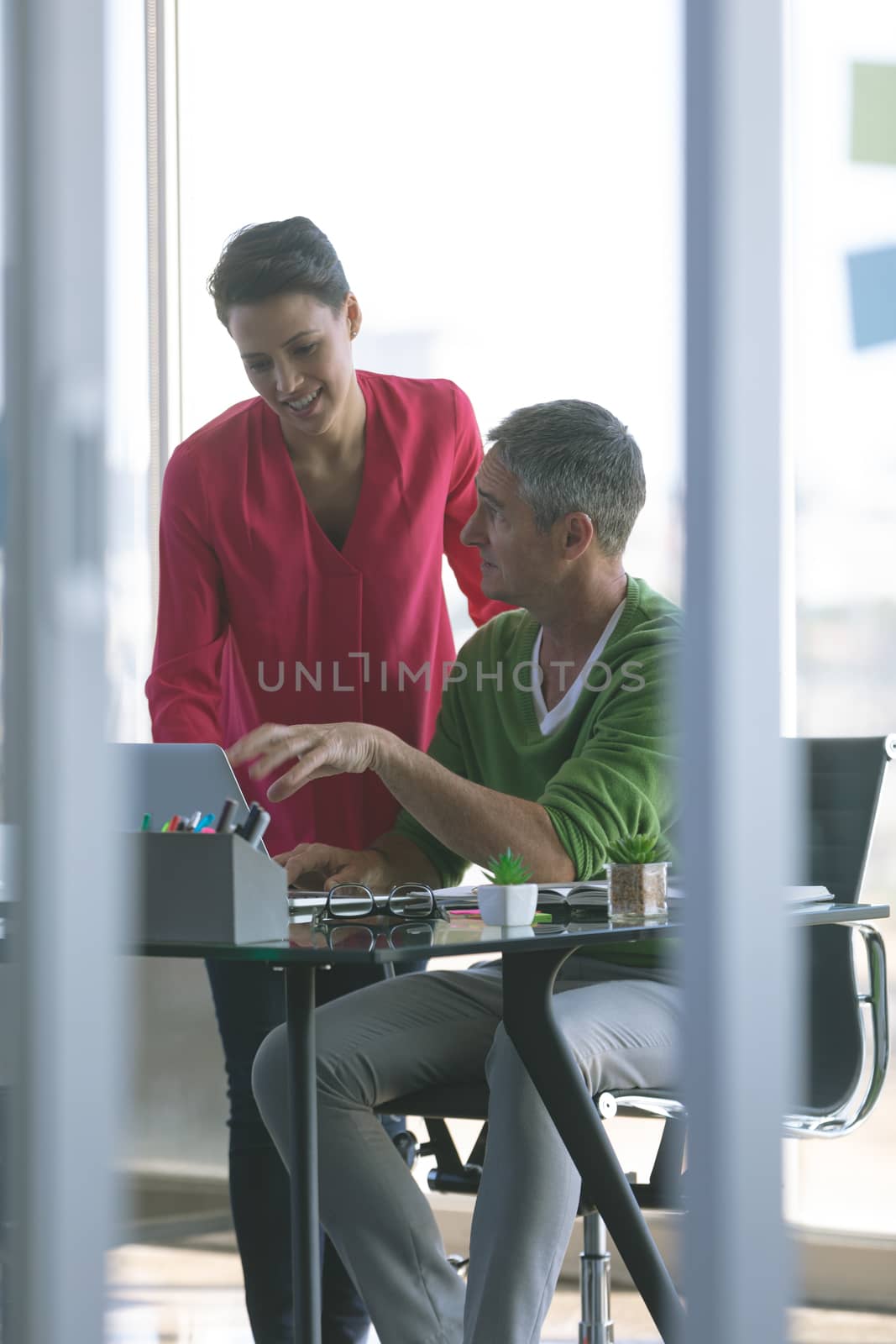 Front view of attentive business people discussing over laptop at desk in office