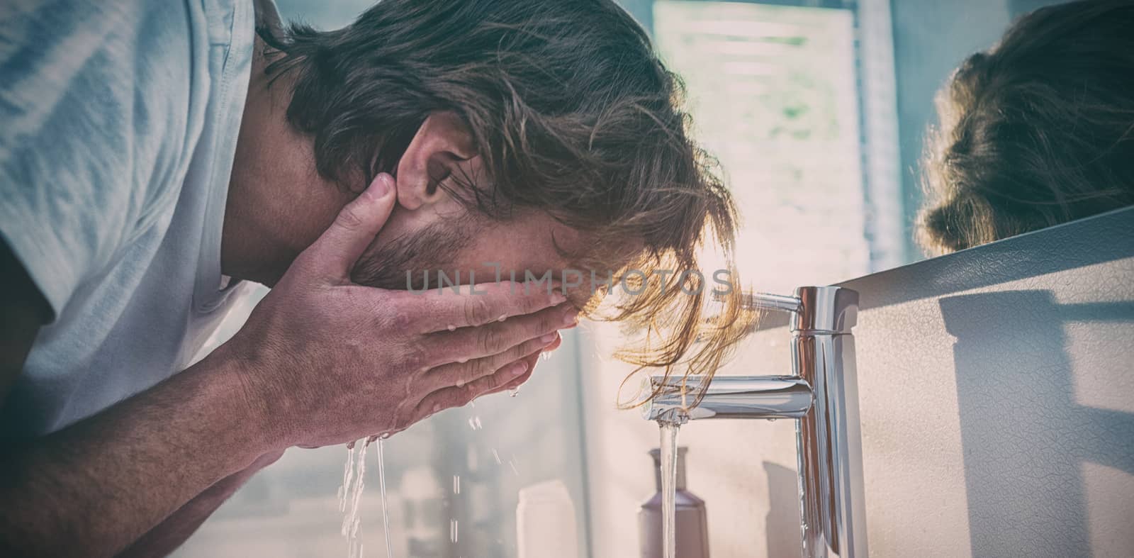 Man washing his face with water in bathroom at home