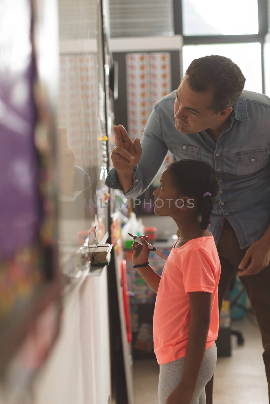 Side view of a Caucasian teacher learning mathematics to a metis school girl on a whiteboard against blur background