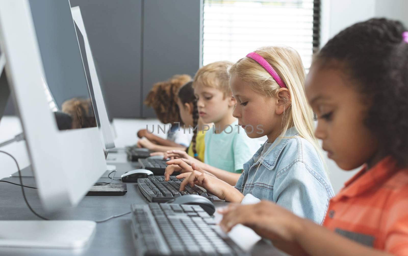 School kids using computer in school  by Wavebreakmedia