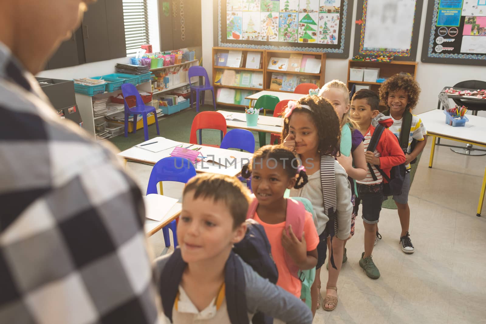 Front view of school kids standing and forming a queue in classroom at school