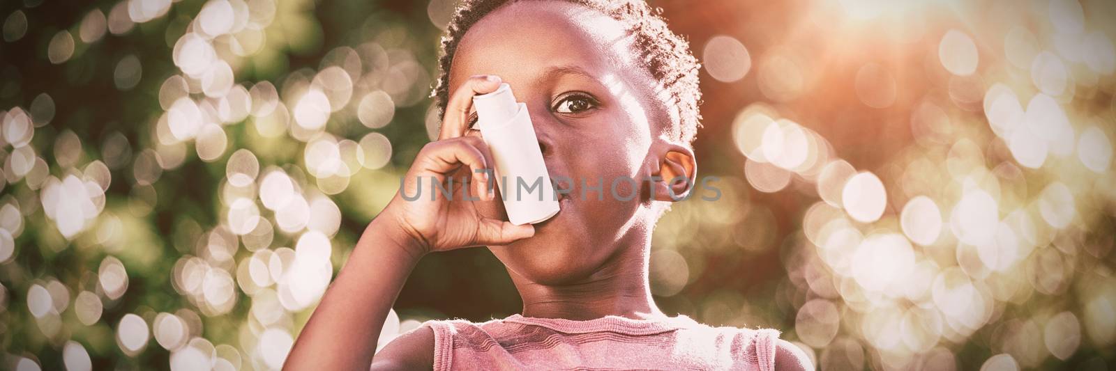 Boy using a asthma inhalator in a park