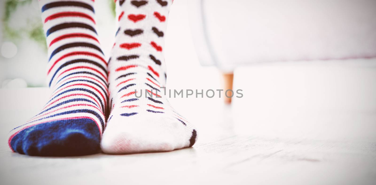 Low section of girl wearing patterned socks while standing at home