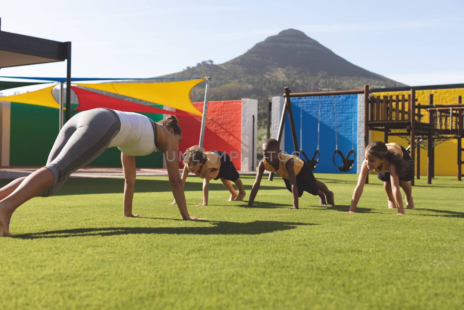 Trainer teaching yoga to students in school playground by Wavebreakmedia