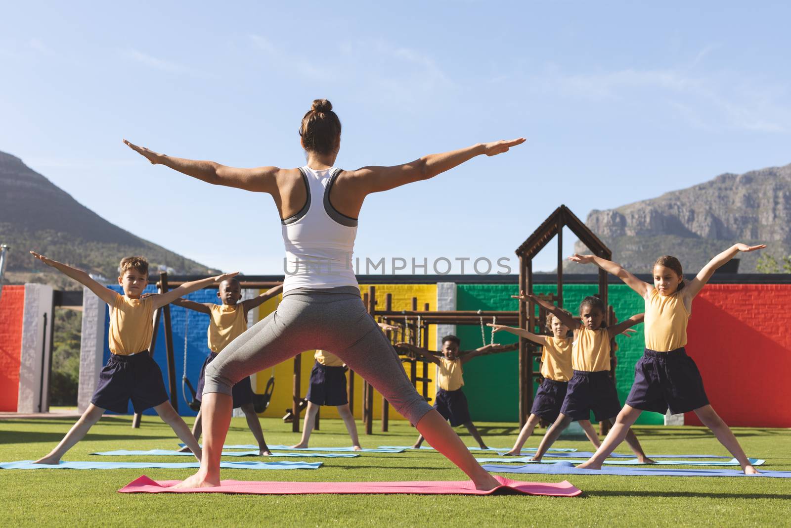 Trainer teaching yoga to students in school playground by Wavebreakmedia