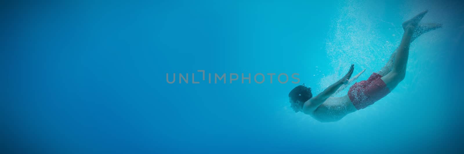 Full length side view of a young man swimming underwater