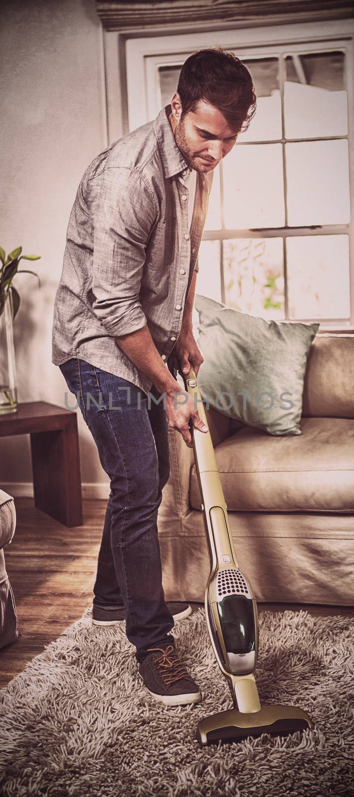 Man cleaning a carpet with a vacuum cleaner at home