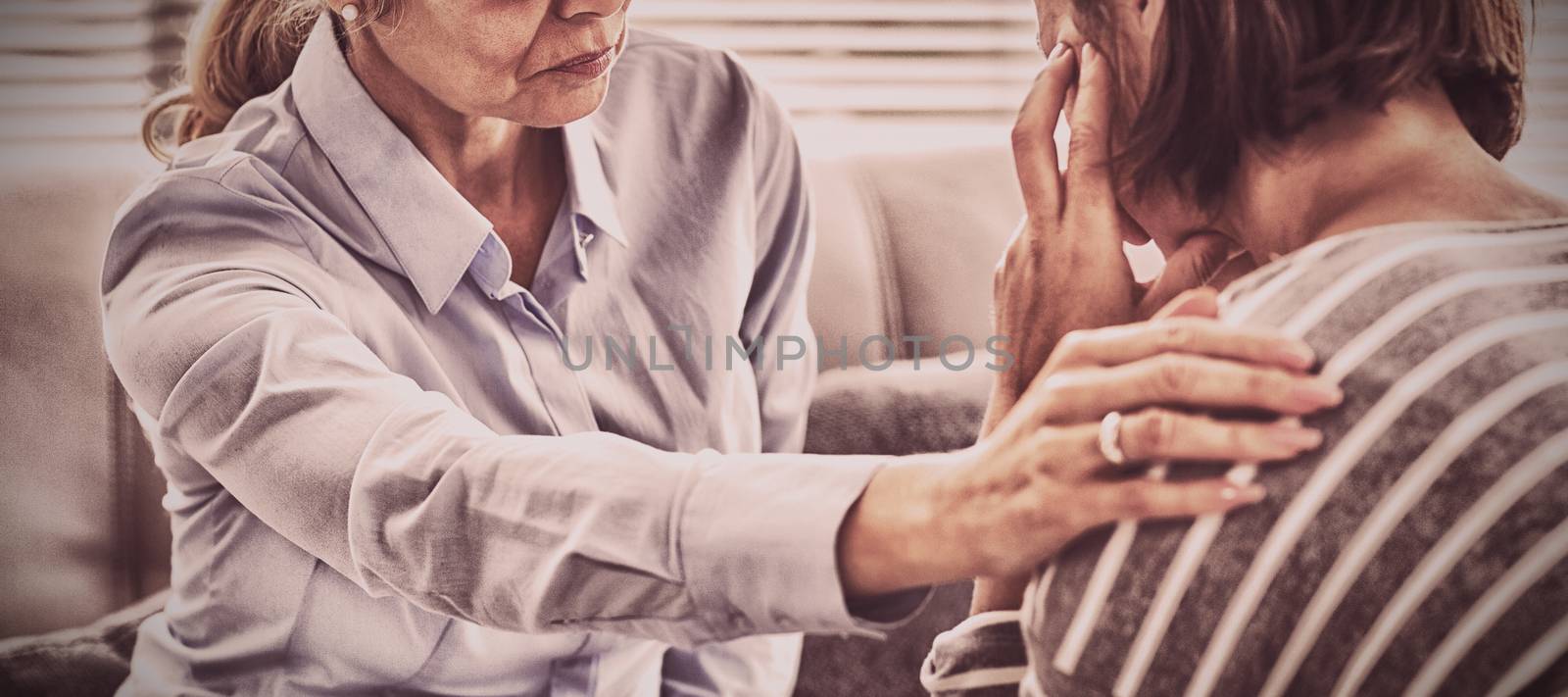 Therapist comforting patient on sofa at home