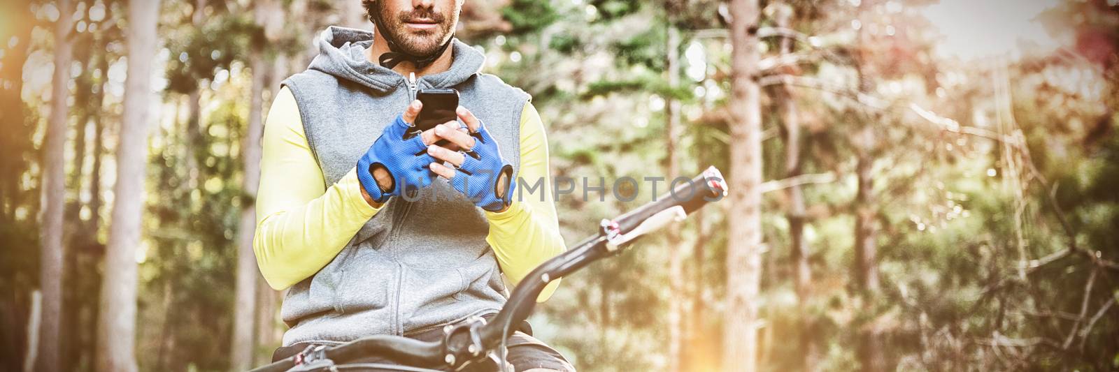 Mountain biker using mobile phone in the forest