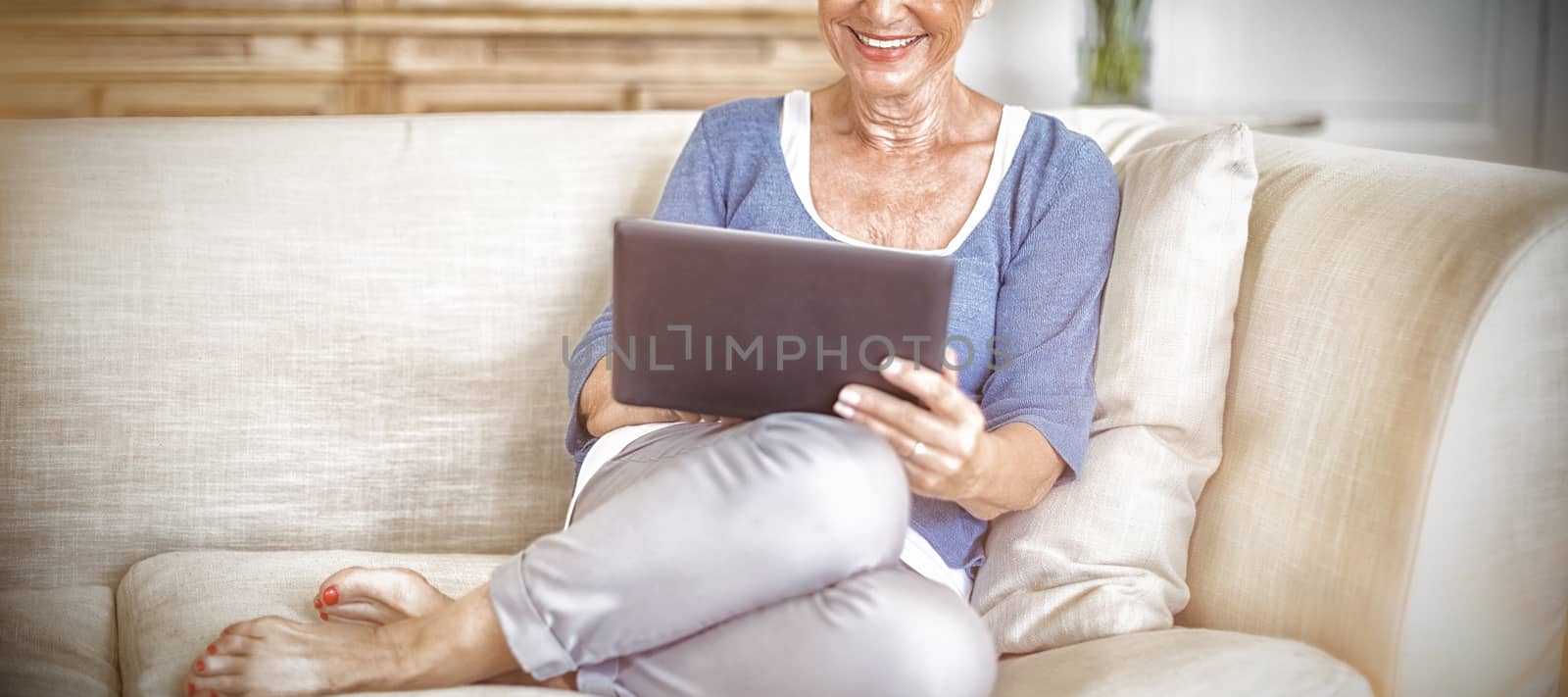 Senior woman using digital tablet in living room at home