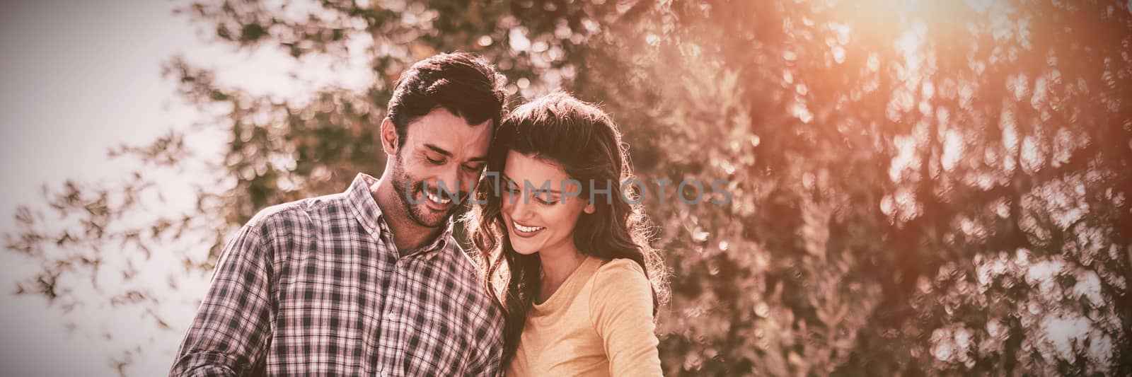 Smiling young couple using mobile phone together while standing at farm
