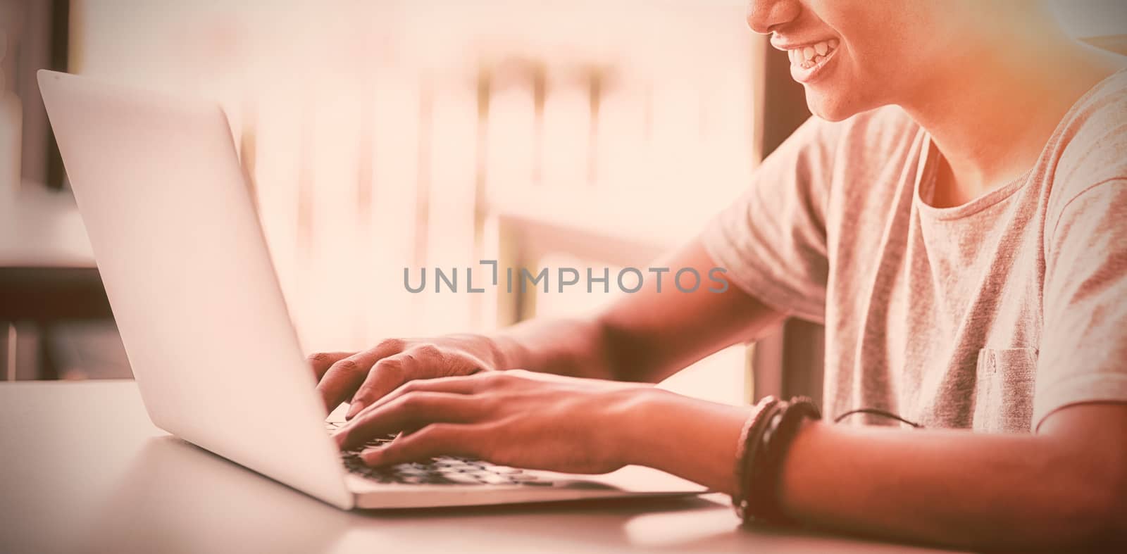 Happy schoolboy using laptop in classroom at school