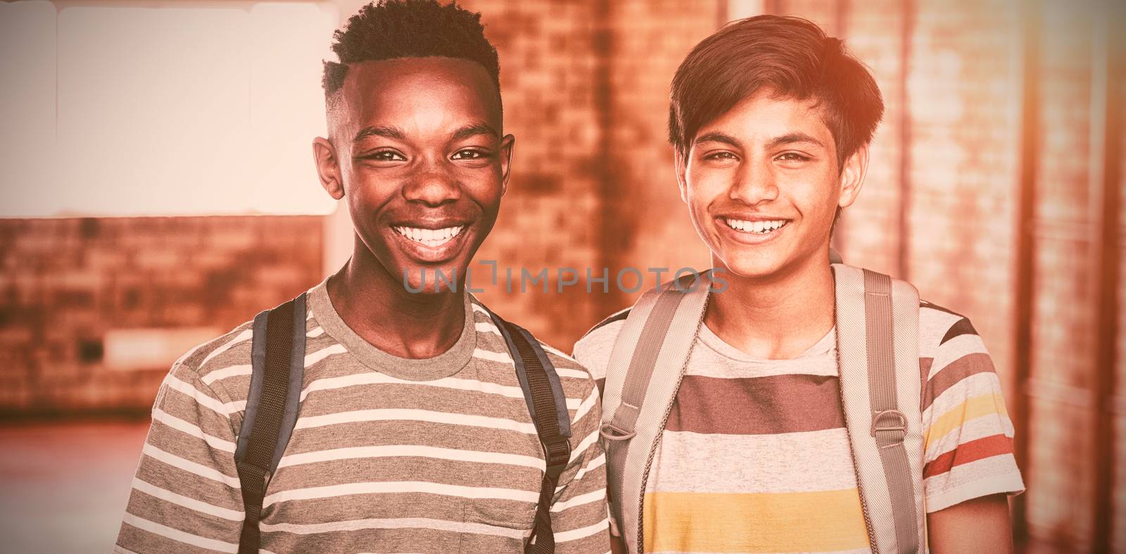 Portrait of happy schoolboys with schoolbag standing in campus at school