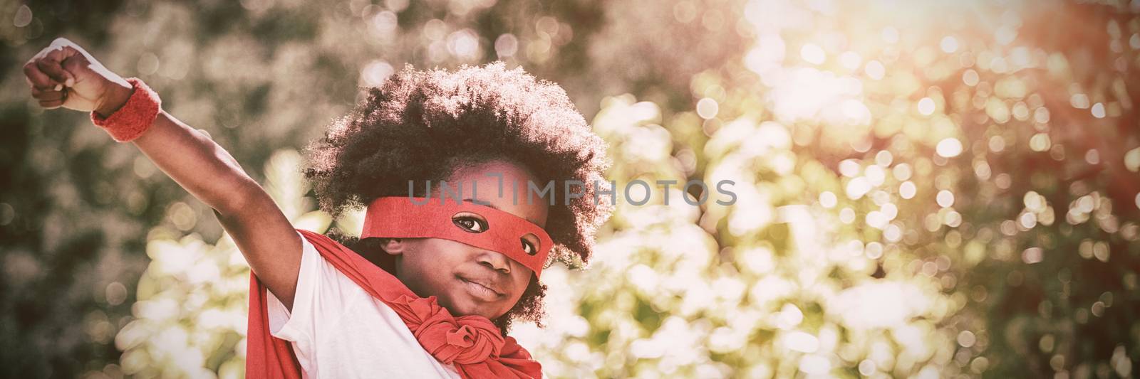 Portrait of boy in red cape and eye mask over white background
