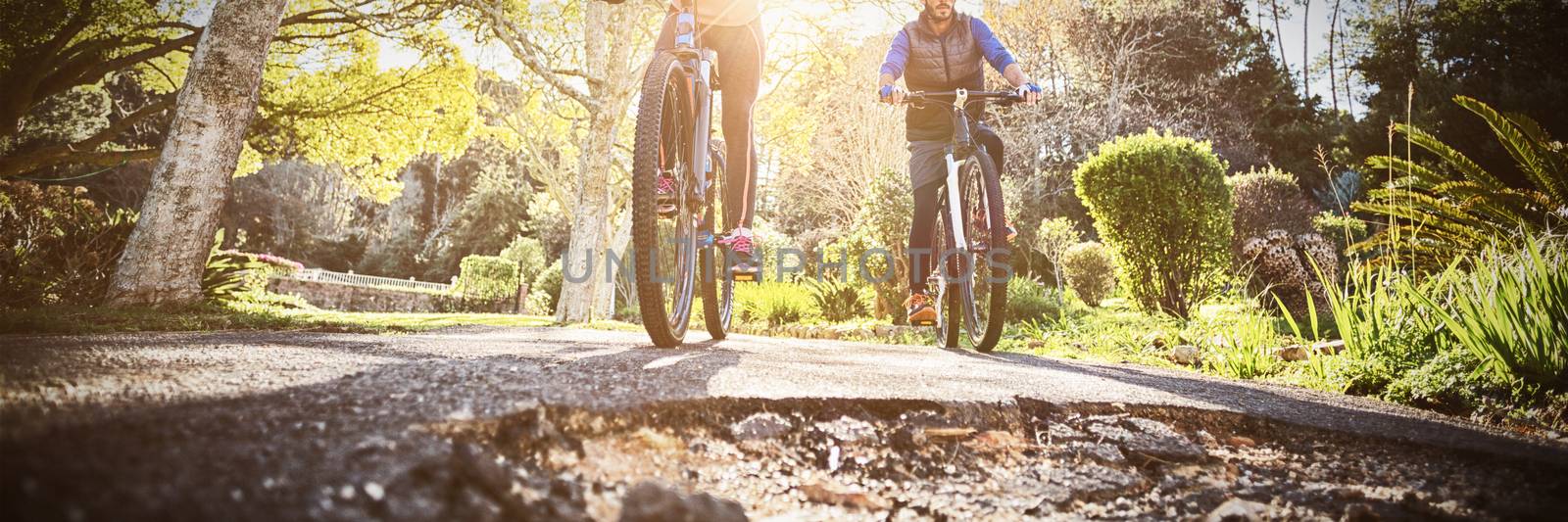 Low angle view of biker couple cycling on countryside road by Wavebreakmedia