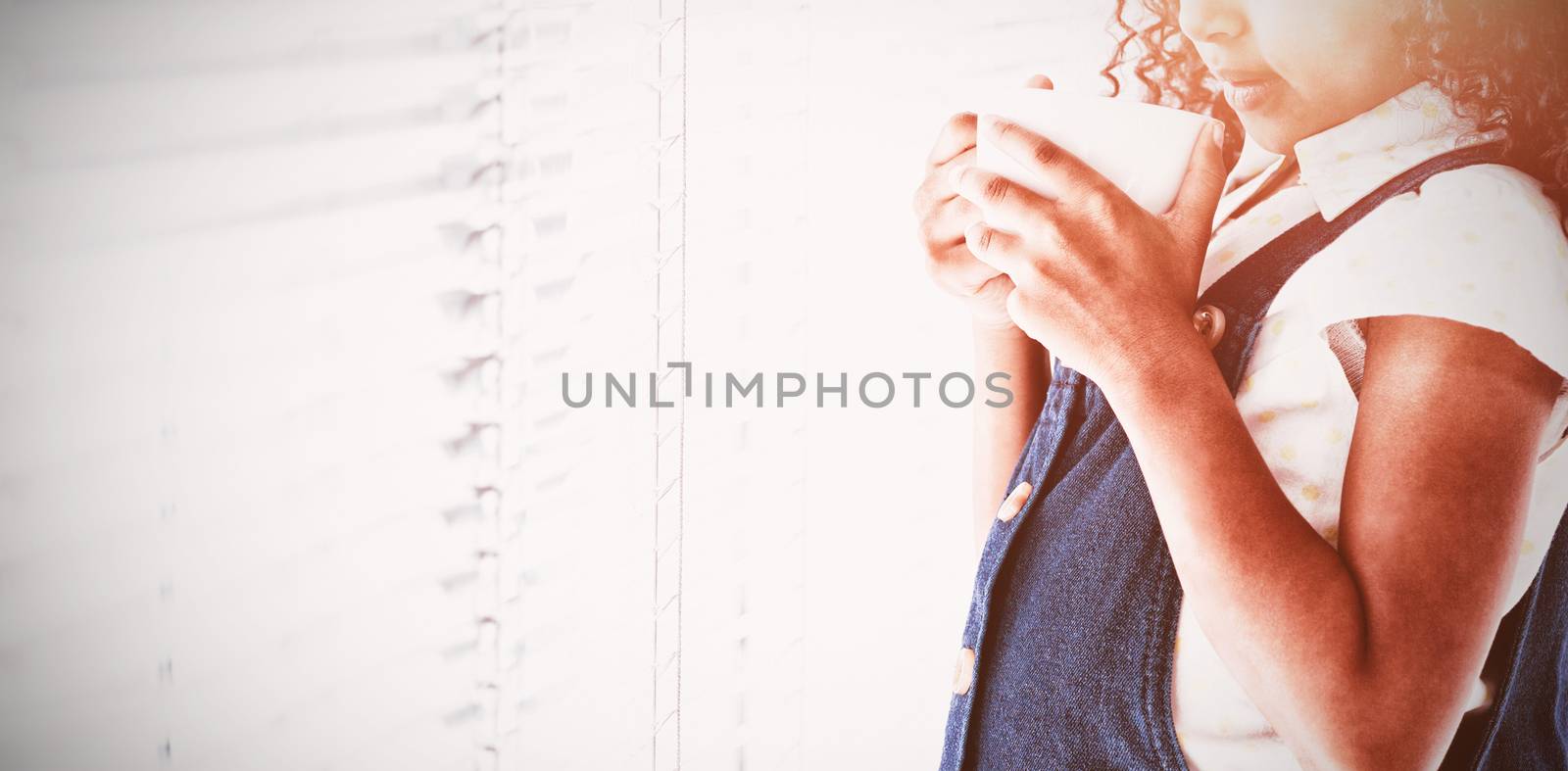 Thoughtful businesswoman with curly hair holding coffee cup while standing b