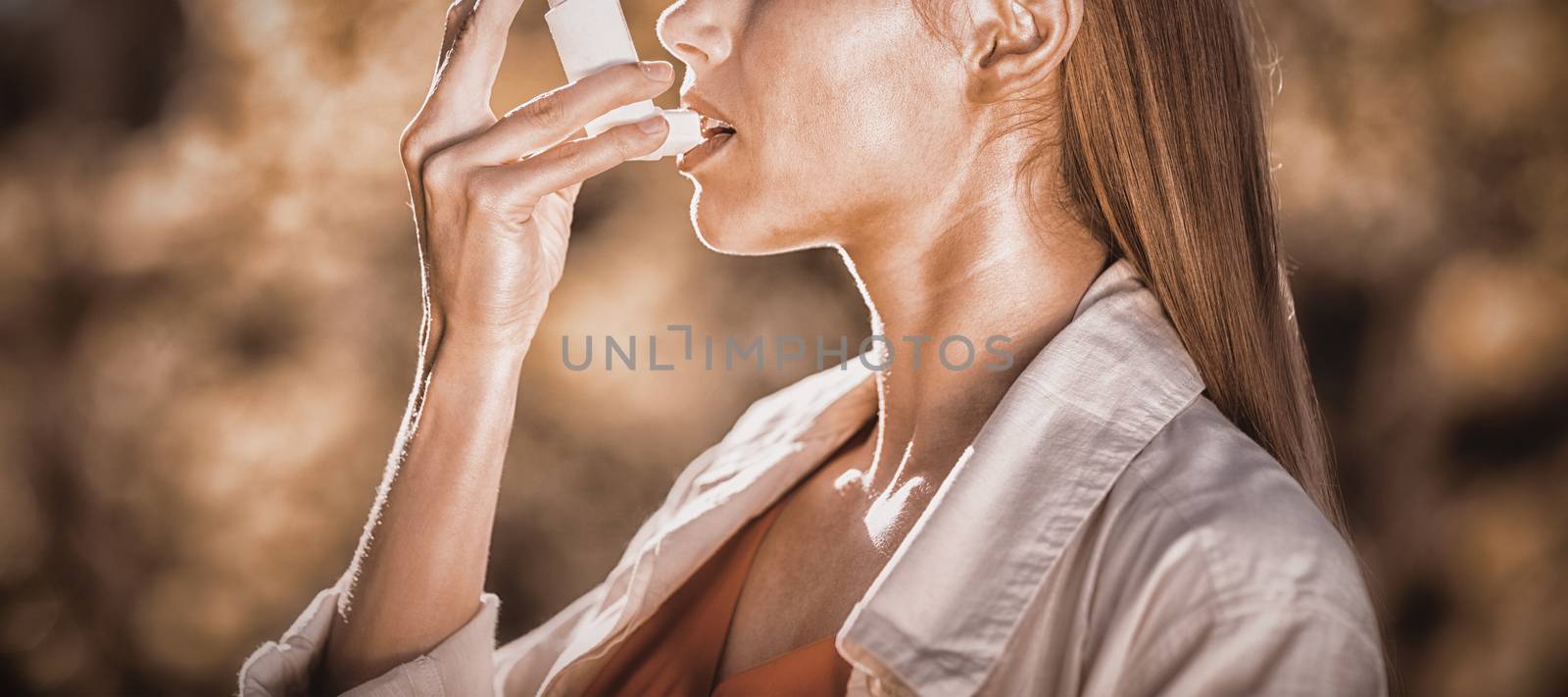 Woman using asthma inhaler in a park